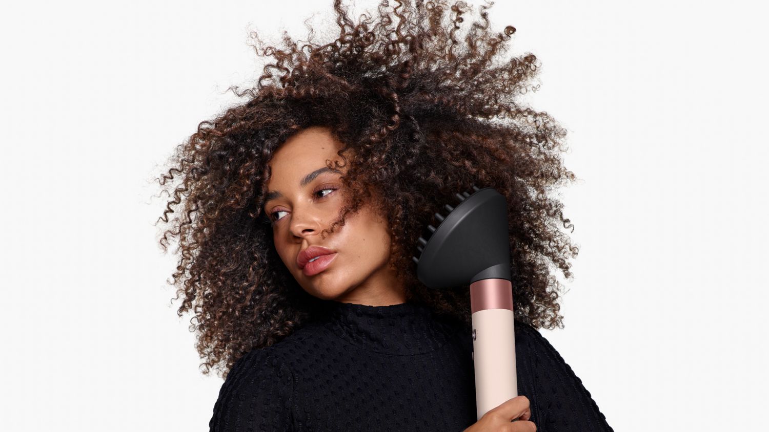 Front-on view of a woman adding volume to her hair with the Dyson Airwrap ID and the Wave+Curl diffuser.